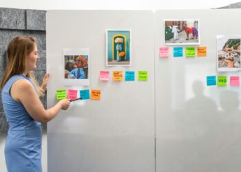 a woman standing in front of a wall with post it notes on it