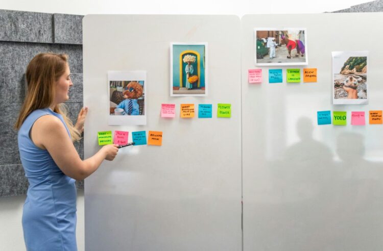 a woman standing in front of a wall with post it notes on it