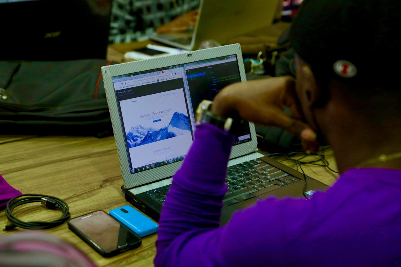 Pria menggunakan laptop di samping ponsel di atas meja