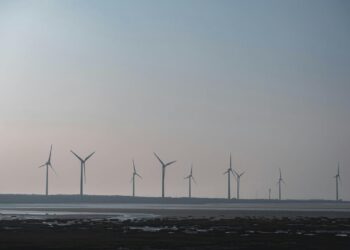 sekelompok kincir angin di kejauhan dengan badan air di depan