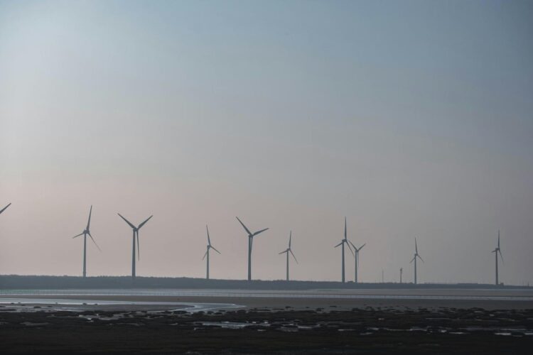 sekelompok kincir angin di kejauhan dengan badan air di depan